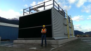 Geoff Holmes of Carbon Engineering, stands in front of a black and gray air contactor outside in BC.