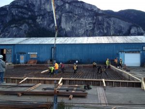 Construction workers labour outside on Carbon Engineering's Direct Air Capture equipment, with the Squamish Chief in the background.